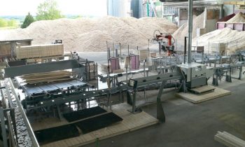 Die neue Anlage zur Optimierung des Werkstoffs Holz beinhaltet eine Kappsäge (vorn) und einen Stapelroboter (hinten) (Bild: Paul Maschinenfabrik).
