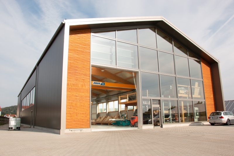 Transparente Fertigung: In der neuen Produktionshalle werden Dach- und Wandelemente für Massivholzhäuser gefertigt (Bild: Abus).